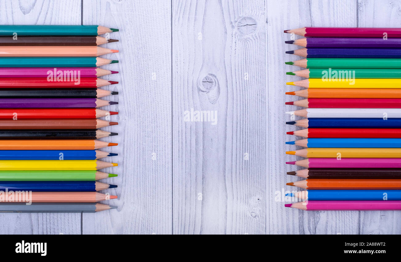 In legno colorato matite, affacciati su un grigio e bianco sullo sfondo di legno Foto Stock
