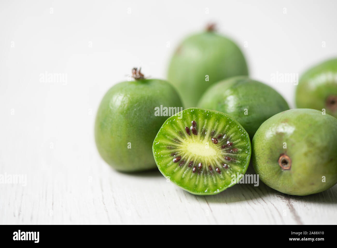 Primo piano di alcuni maturi frutti di bosco kiwi su un bianco tavolo rustico Foto Stock