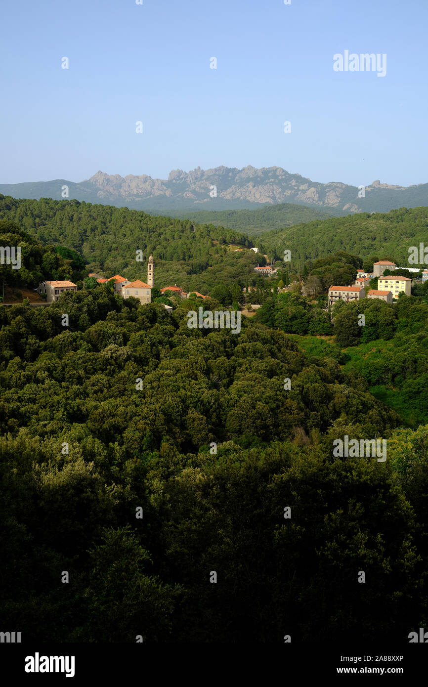 La montagna verde paesaggio interiore e il villaggio di Carbini con le Aiguilles de Bavella in distanza, Alta Rocca, Corse-du-Sud Corsica Francia Foto Stock