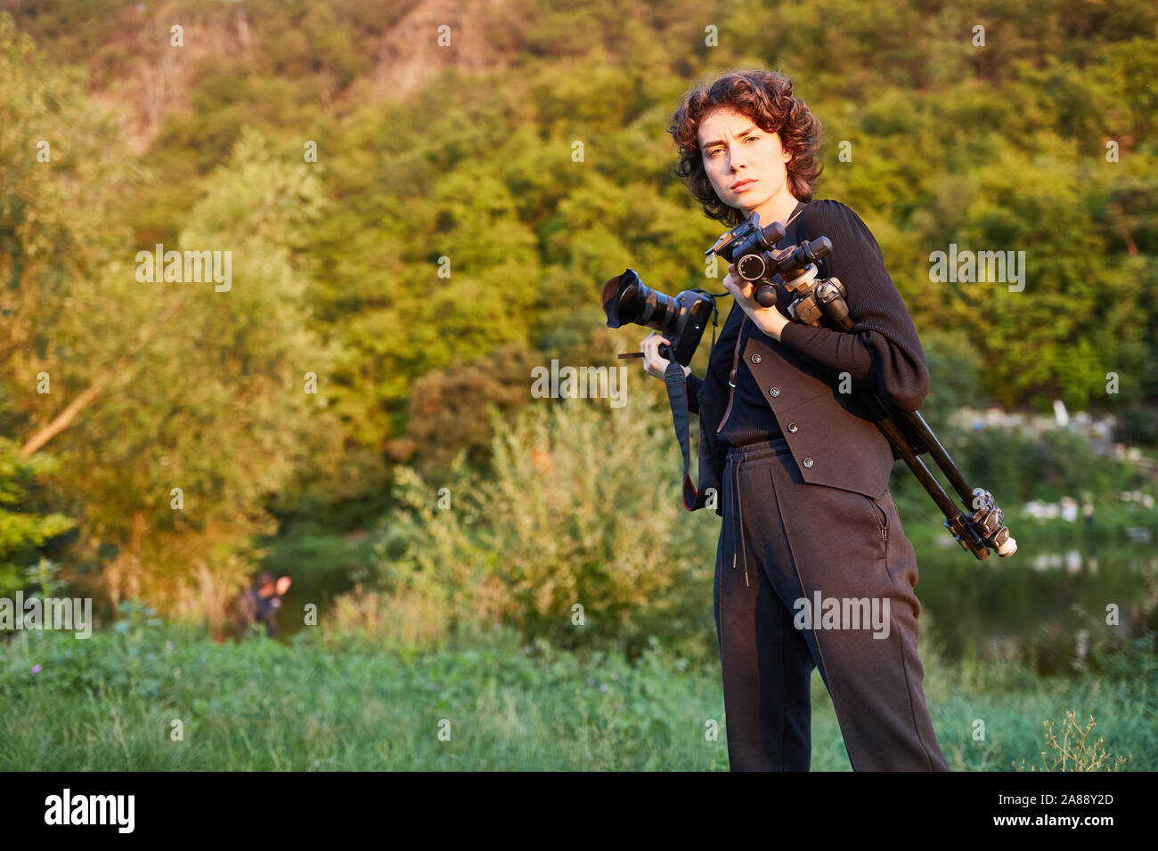 Giovane donna con attrezzatura fotografica come fotografo di paesaggio in natura Foto Stock