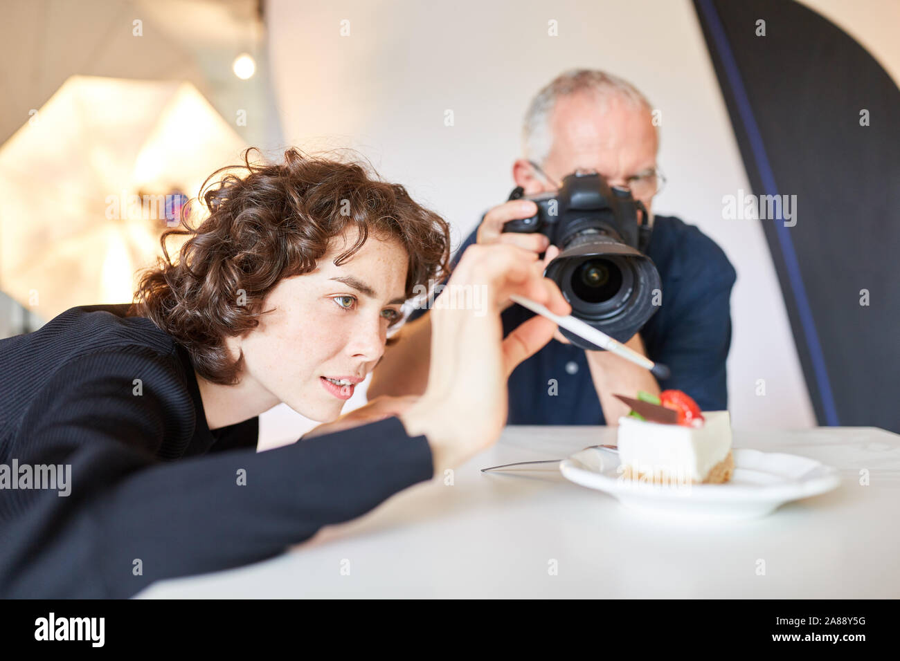 Stilista di alimentare con spazzola prepara photo shoot con un pezzo di torta Foto Stock