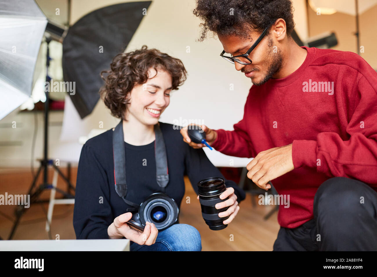 Fotografo e assistente di foto insieme a pulire la lente della fotocamera Foto Stock