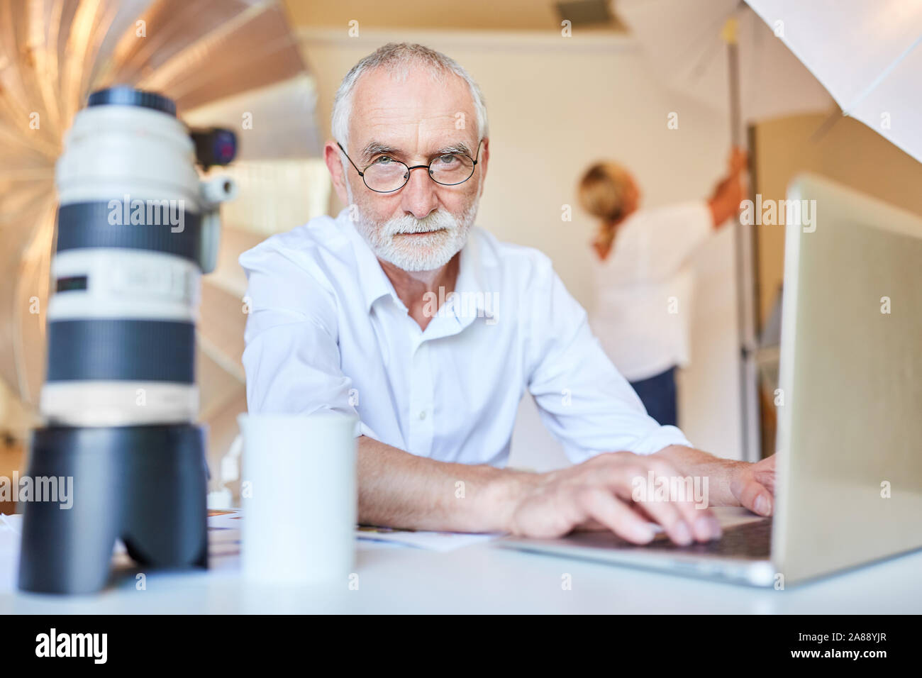 Fotografo senior presso il laptop. Computer durante l'editing di immagini Foto Stock