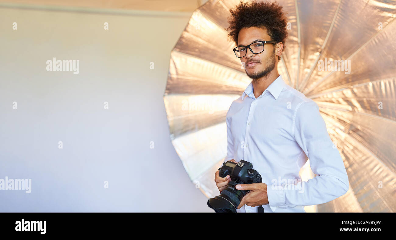 Sicuro di sé il giovane come un fotografo con la fotocamera nella foto studio Foto Stock