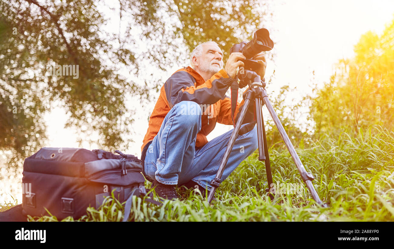 Fotografo con fotocamera e treppiede in natura nella fotografia di paesaggi Foto Stock