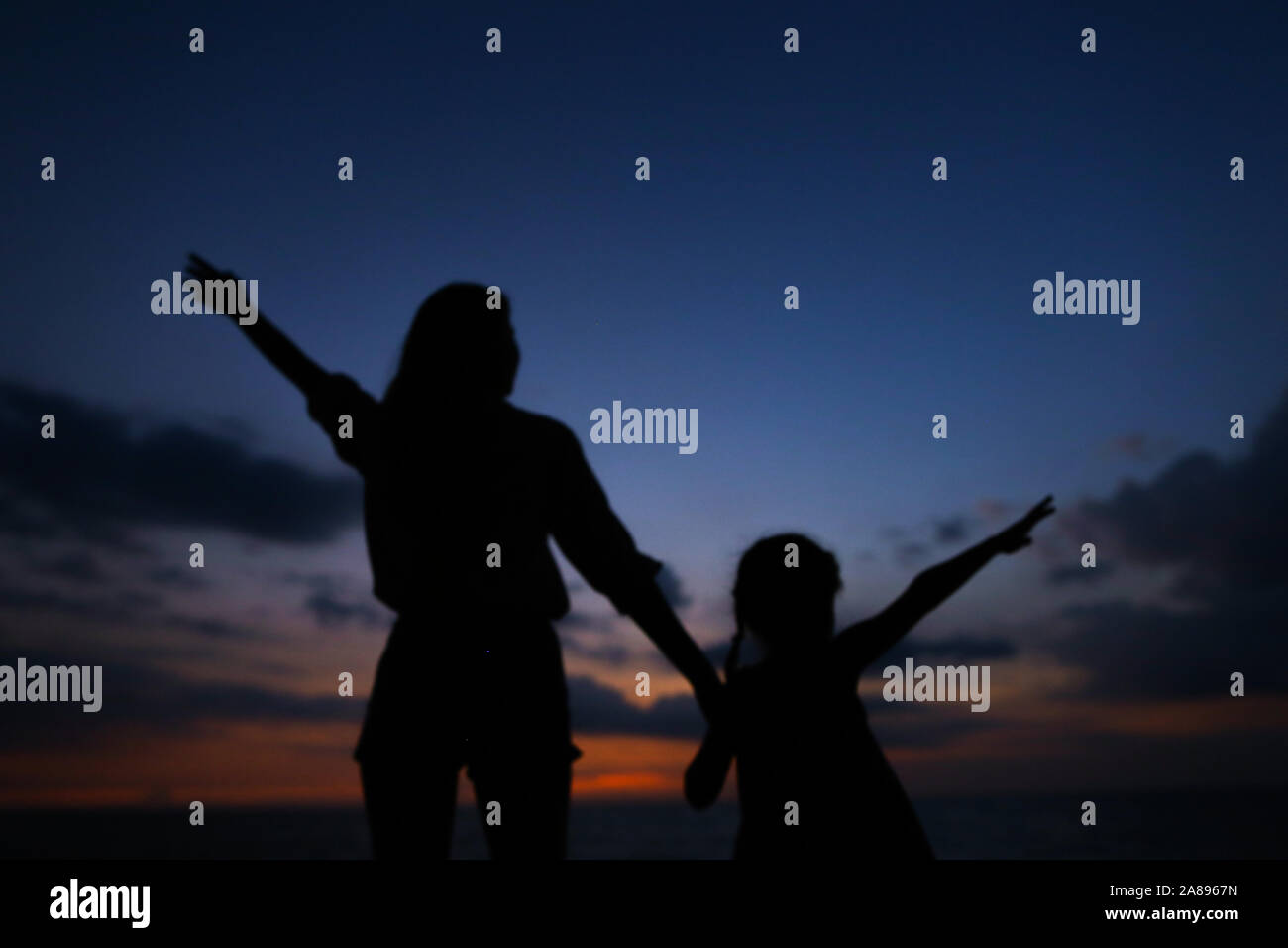 Black silhouette di donna e bambina camminando in vening, tramonto sullo sfondo. Foto Stock