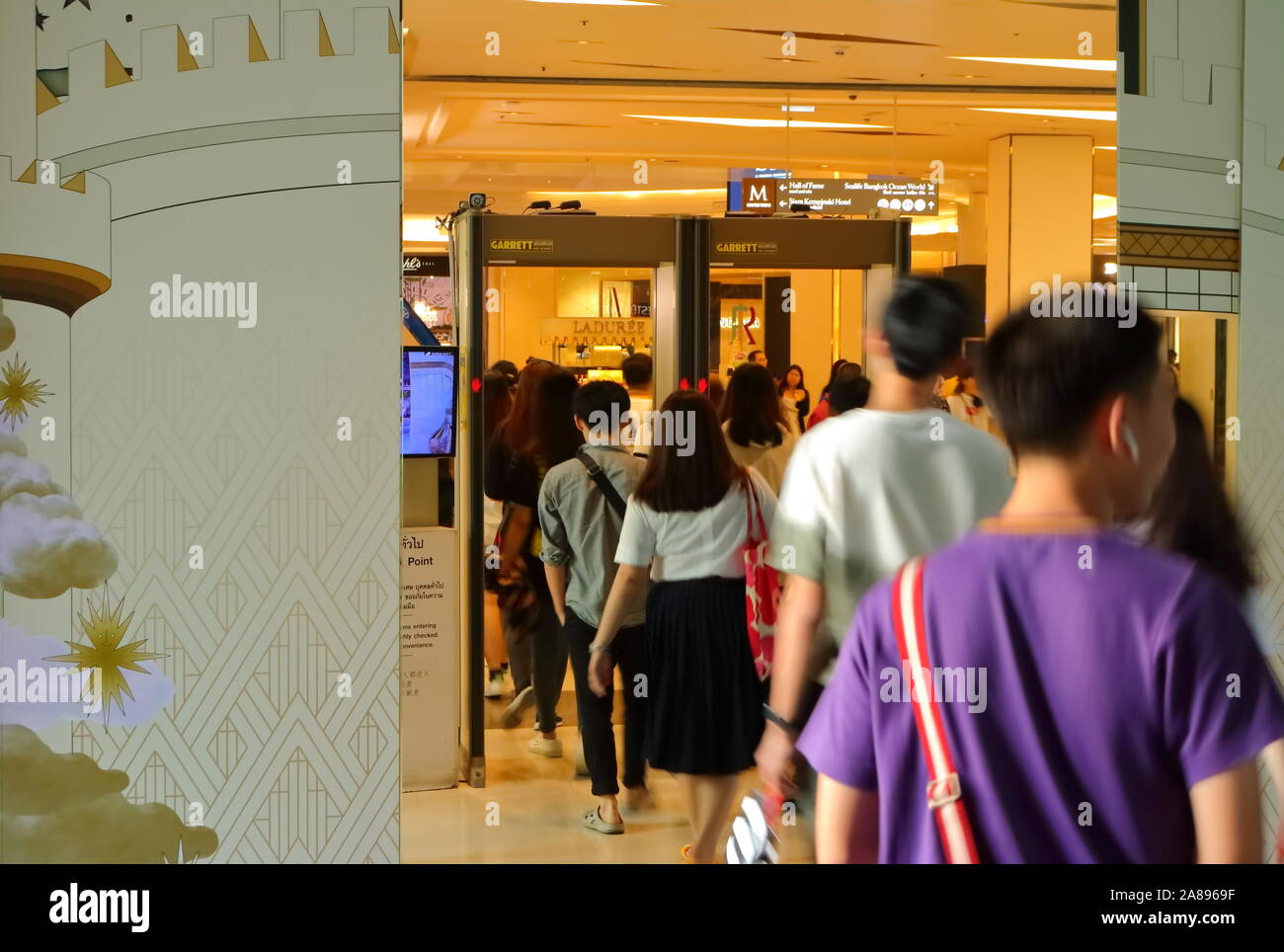 Bangkok, Tailandia - 8 Novembre 2019 : sfocato il movimento di persone in fila a piedi attraverso il rivelatore di metalli in entrata del Siam Paragon Shopping Mall Foto Stock