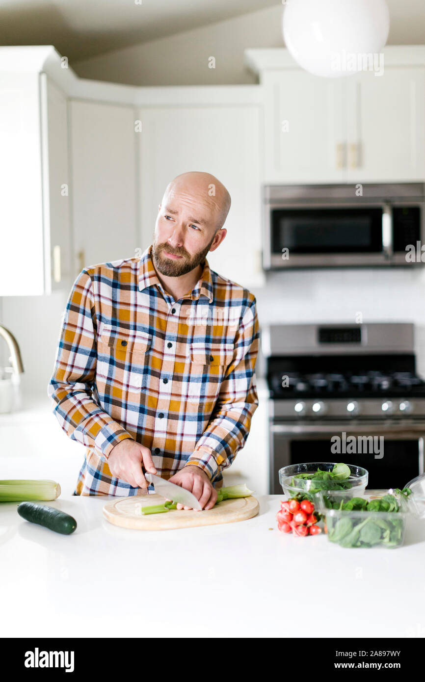 L'uomo tritare verdure in cucina Foto Stock