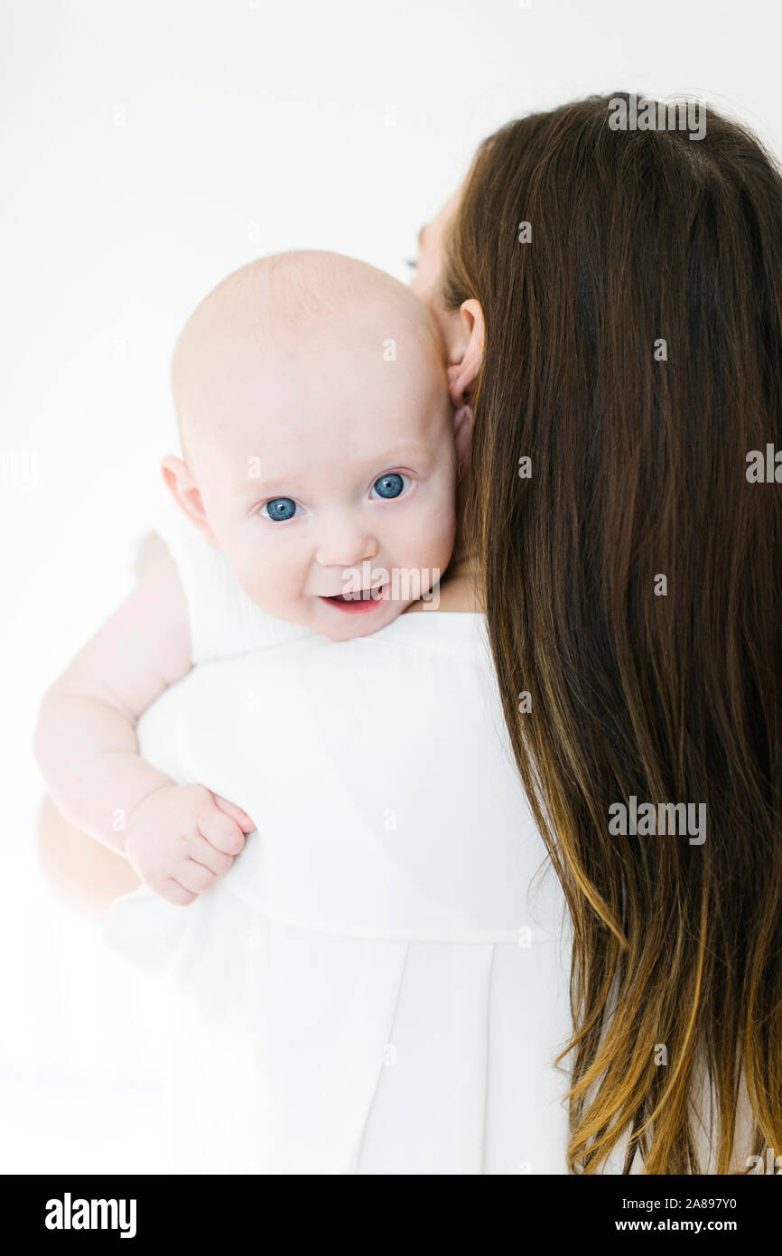Bambino che guarda sopra la spalla della madre Foto Stock
