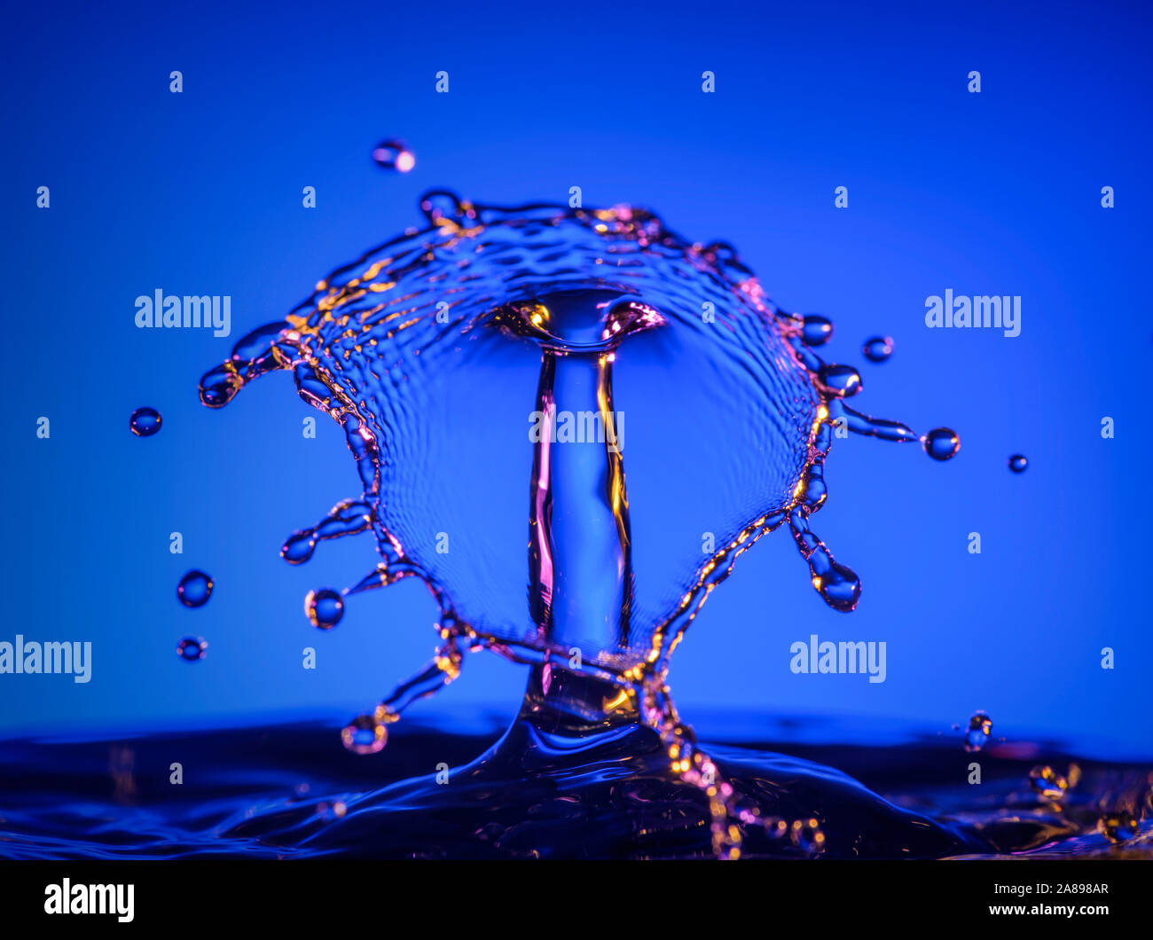 Gli spruzzi di acqua contro sfondo blu Foto Stock