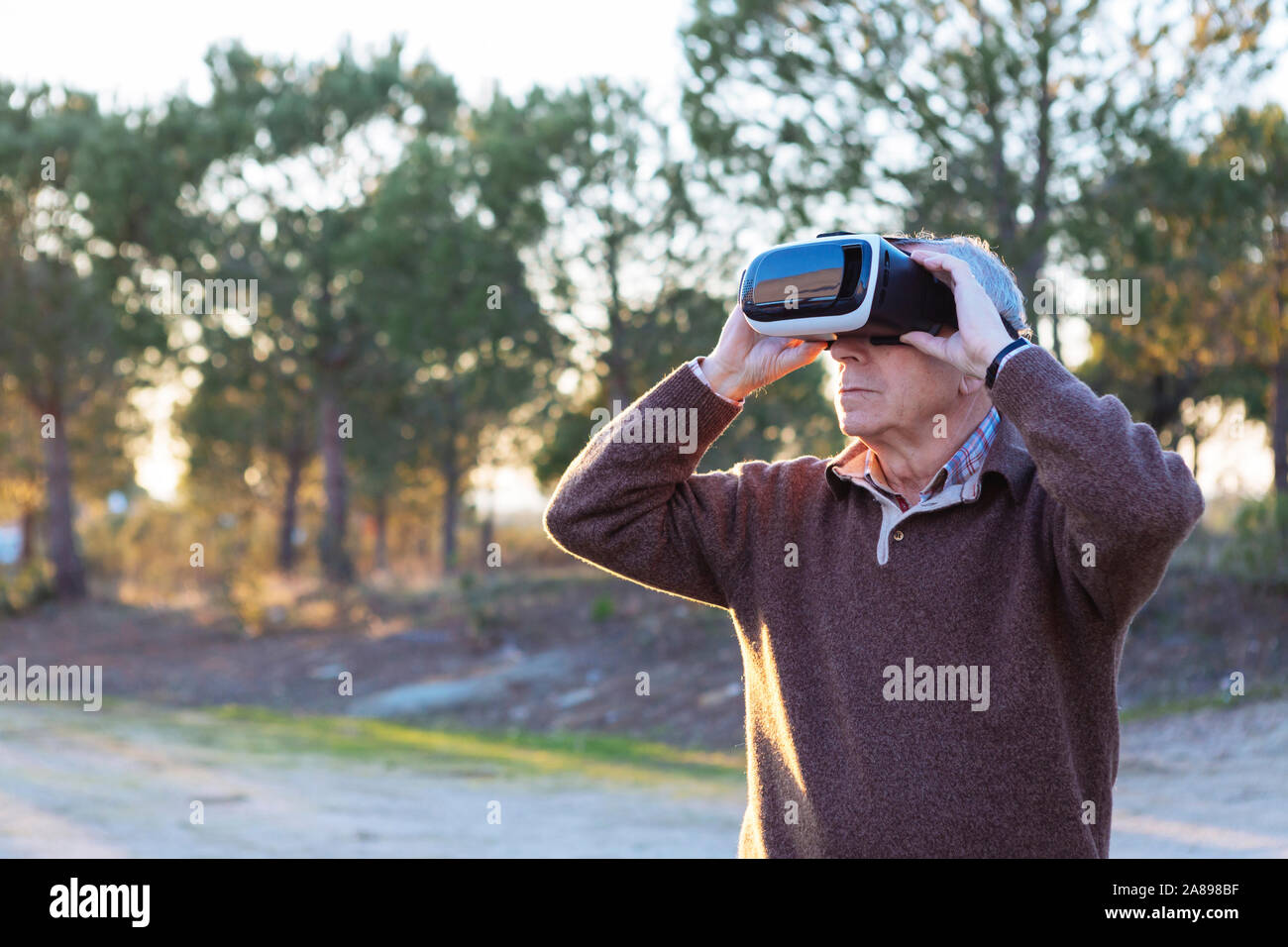 Uomo anziano che indossa un simulatore di realtà virtuale all'aperto Foto Stock