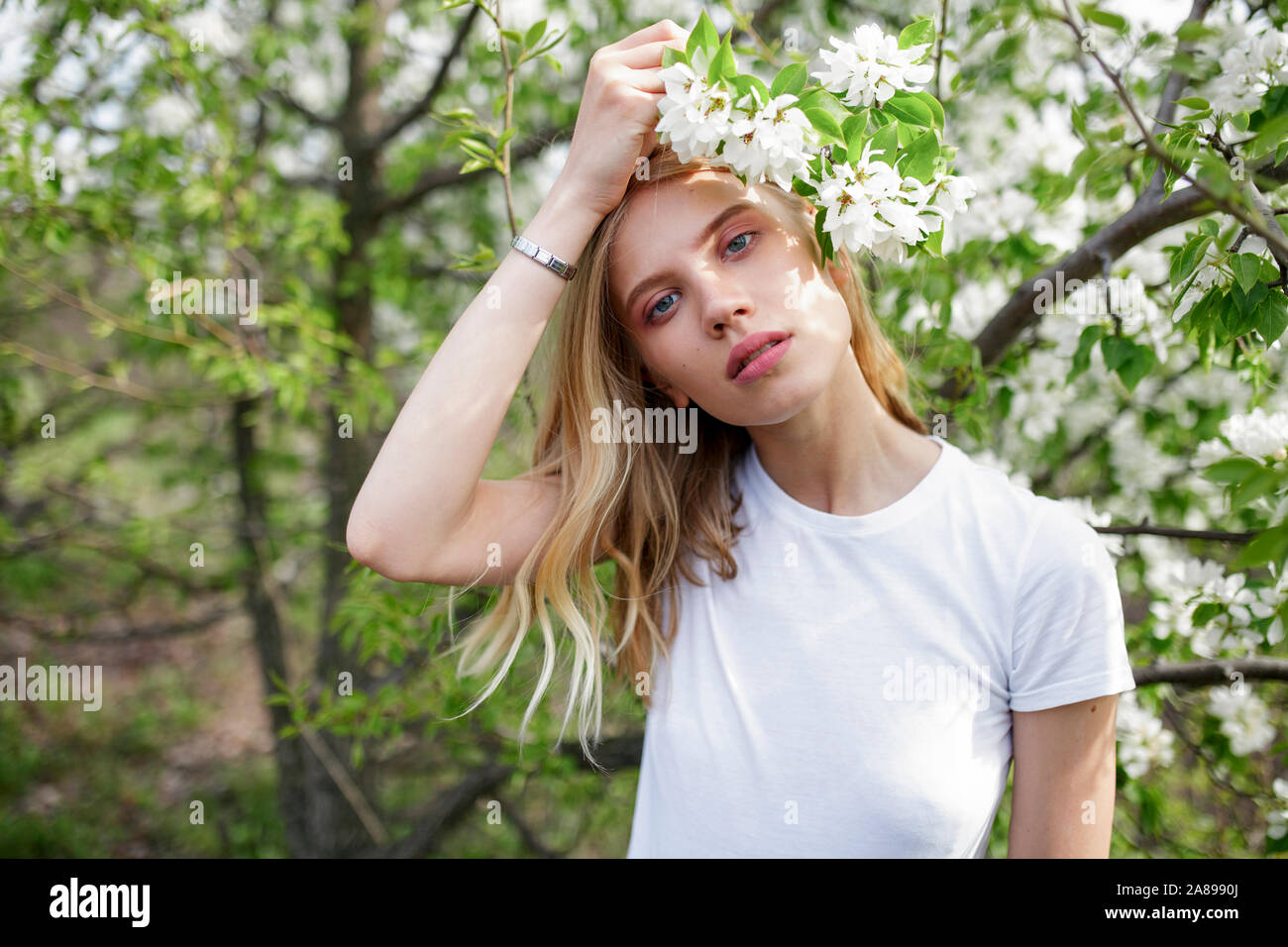 Giovane donna dai capelli biondi tra fiori bianchi Foto Stock