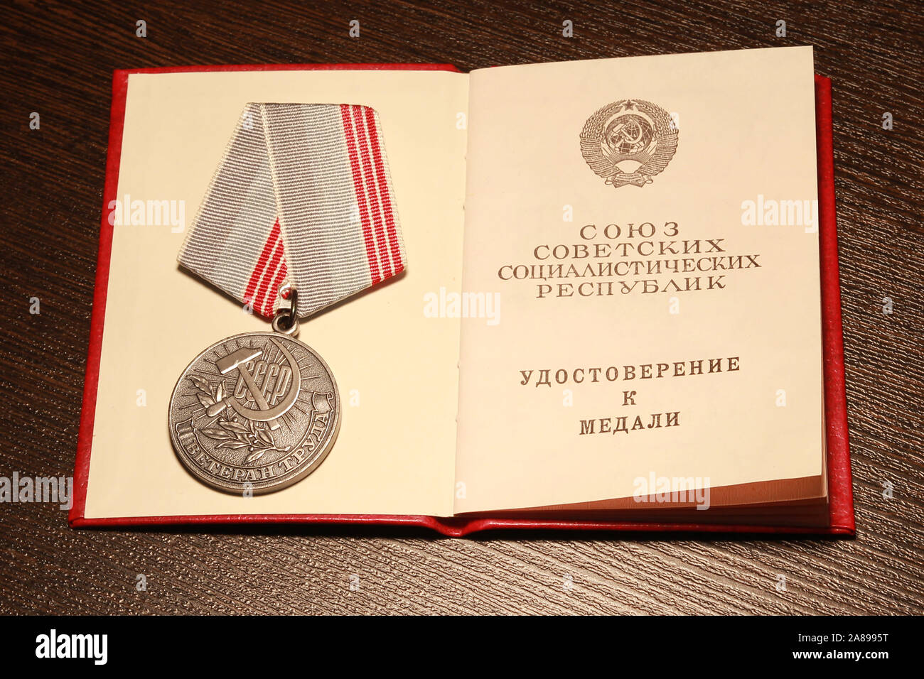 Medaglia sovietica 'Veterano del lavoro', badge e medaglie dell'URSS. La medaglia URSS 'Veteran del lavoro' sul tavolo con un certificato. Traduzione da Ru Foto Stock
