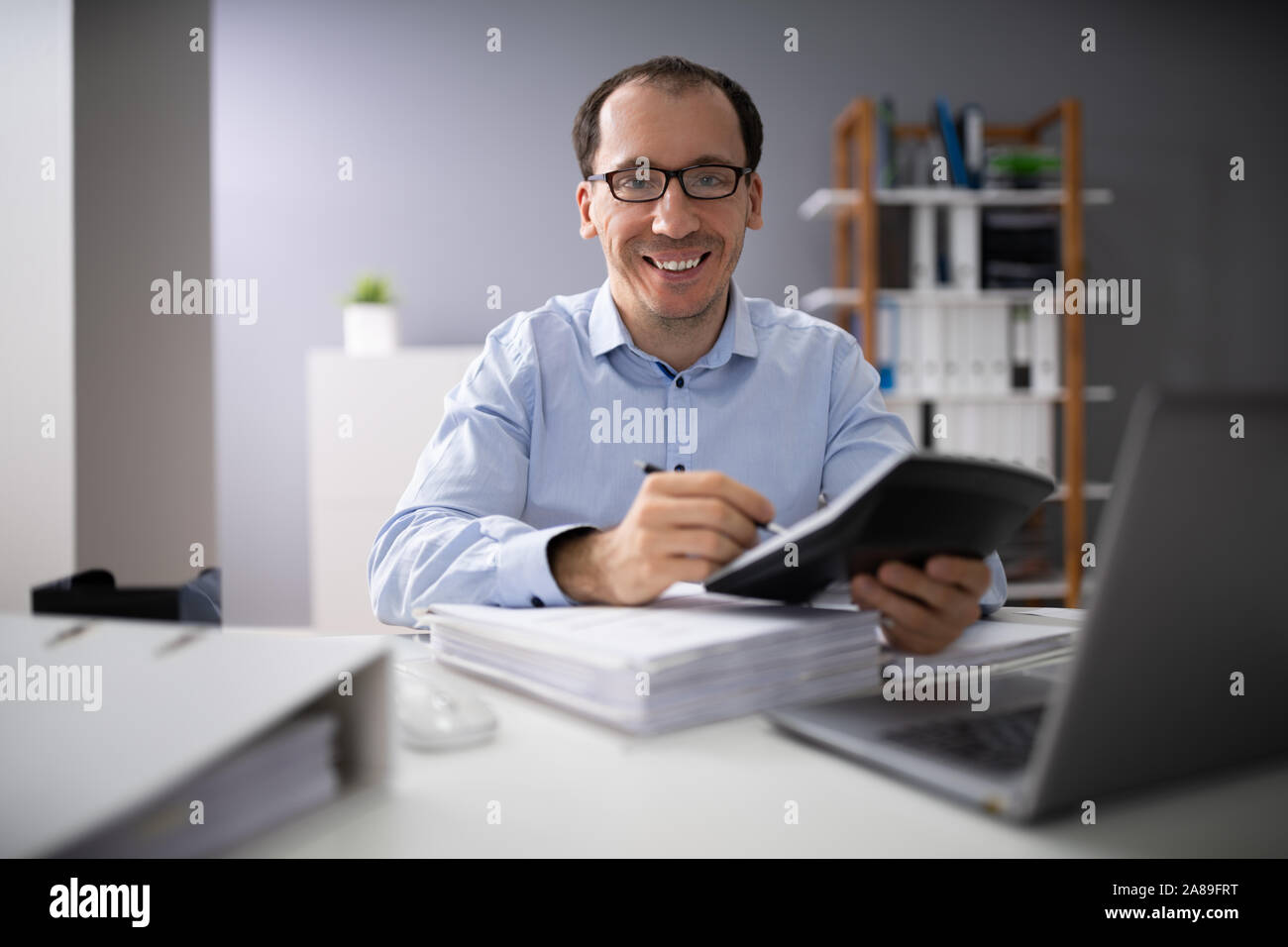 Oltre la spalla di imprenditore il calcolo di fatture utilizzando la calcolatrice Foto Stock