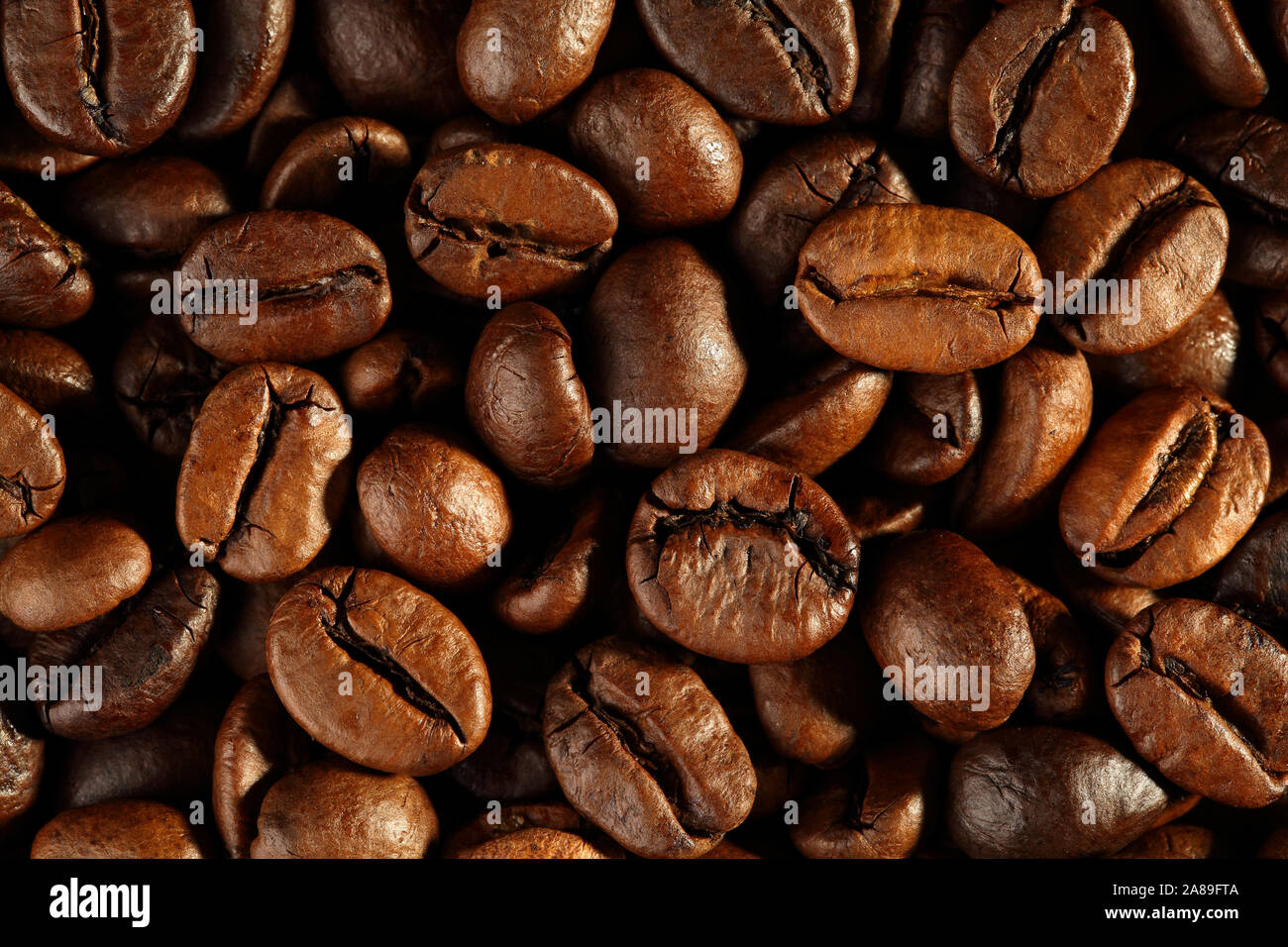 Extreme close up appena tostato, lucido e i chicchi di caffè. Top down vew. Macro food texture di sfondo Foto Stock