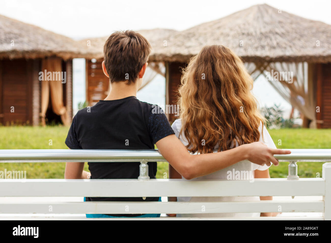 Il ragazzo abbraccia una ragazza seduta su una panchina accanto a ciascun  altro e guardando il mare Foto stock - Alamy