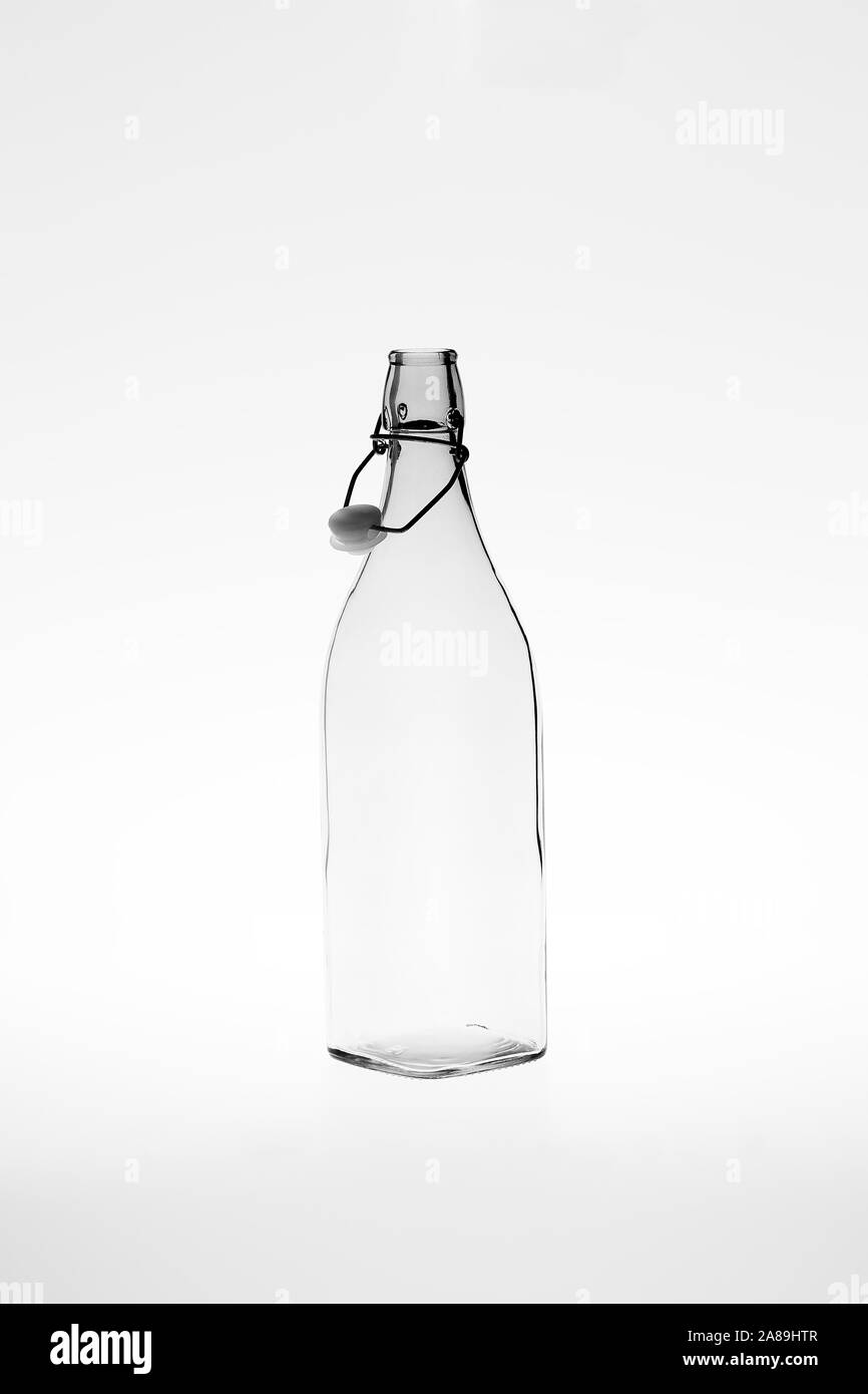 Immagine monocromatica di un retrò quadrato vuoto bottiglia di vetro con un clip per aprire il tappo superiore Foto Stock