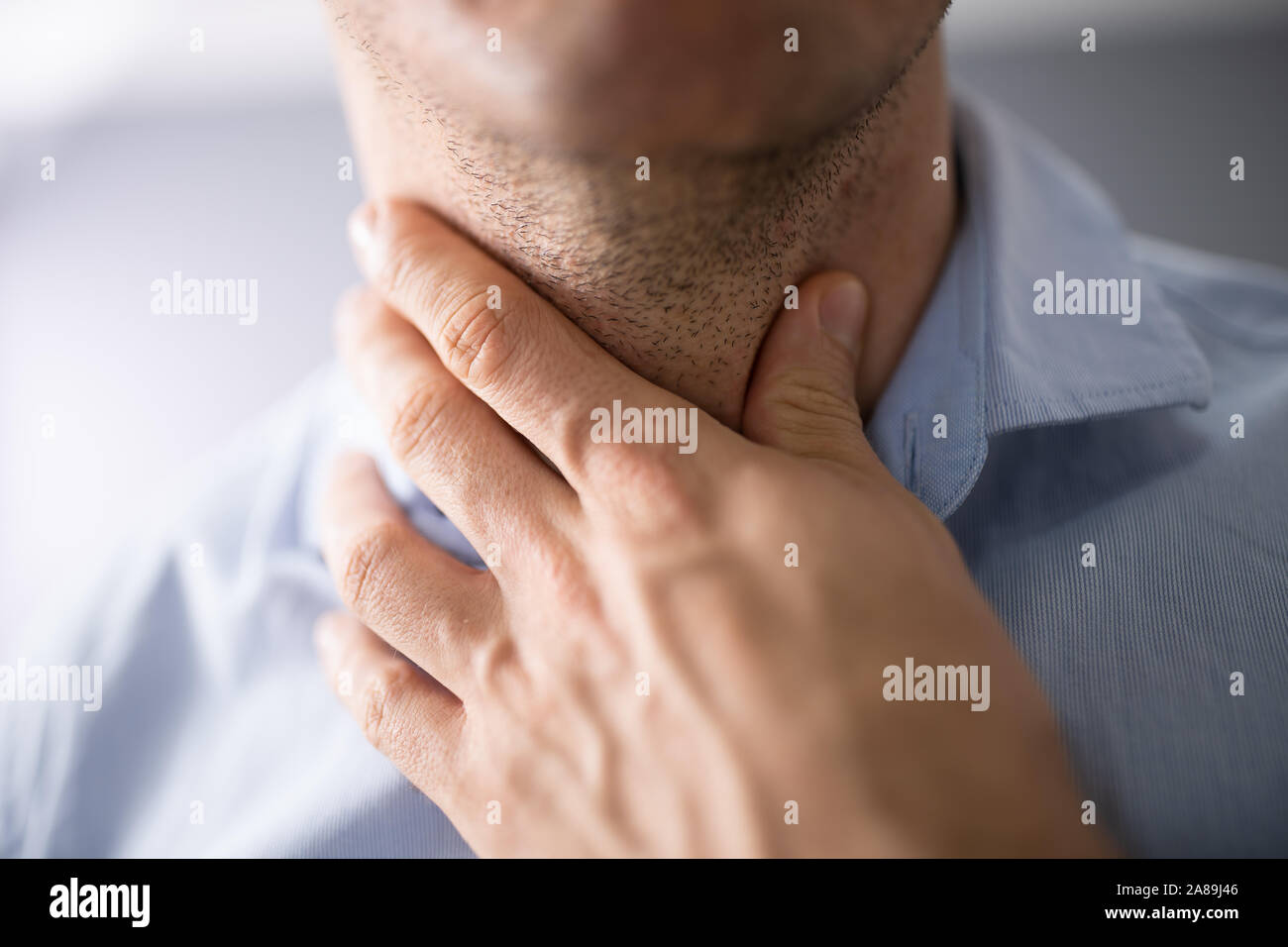 Close-up di una mano di un uomo di toccare il suo mal di gola Foto Stock