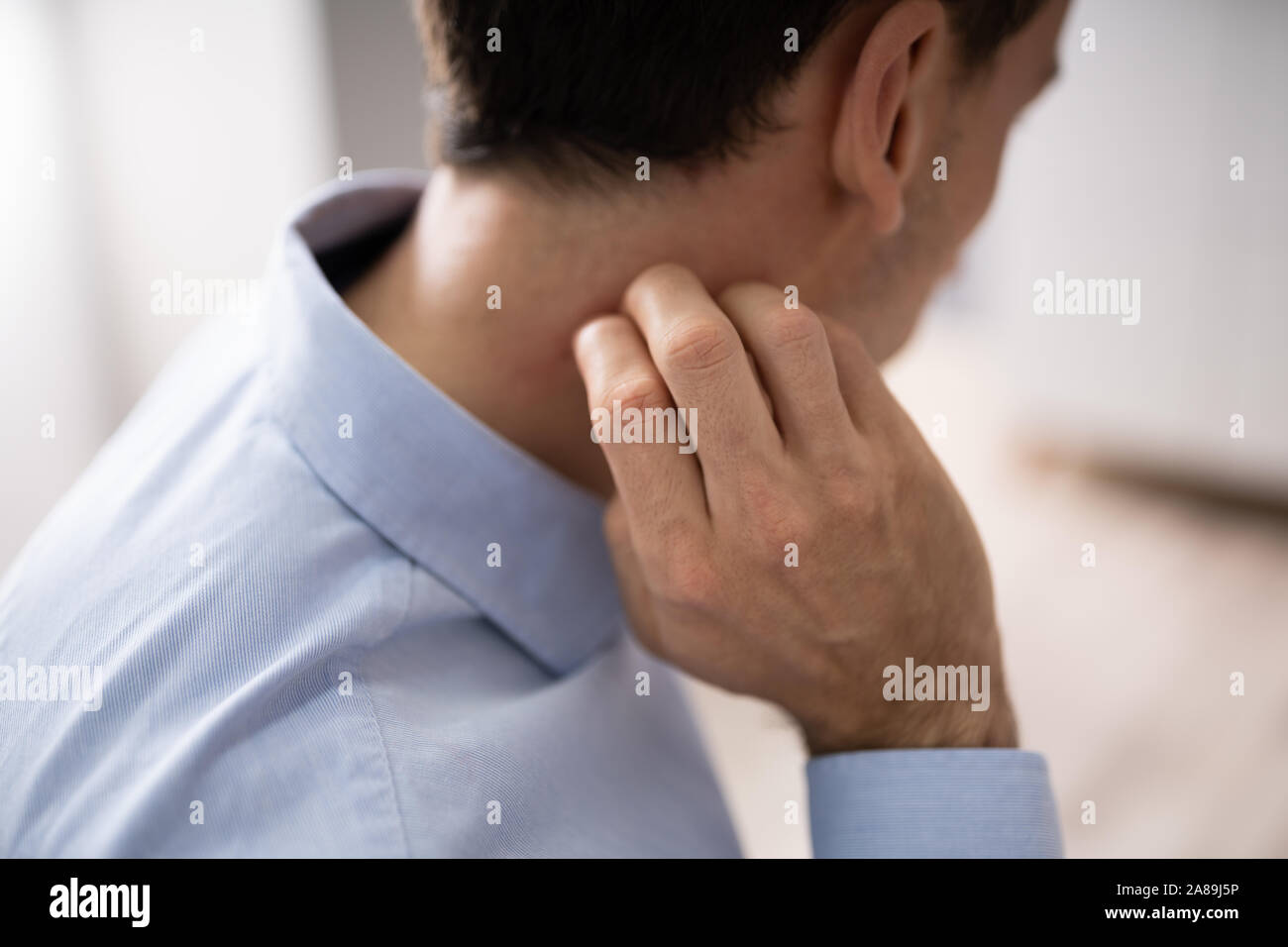 Close-up di una mano di un uomo di graffiare il suo collo Foto Stock