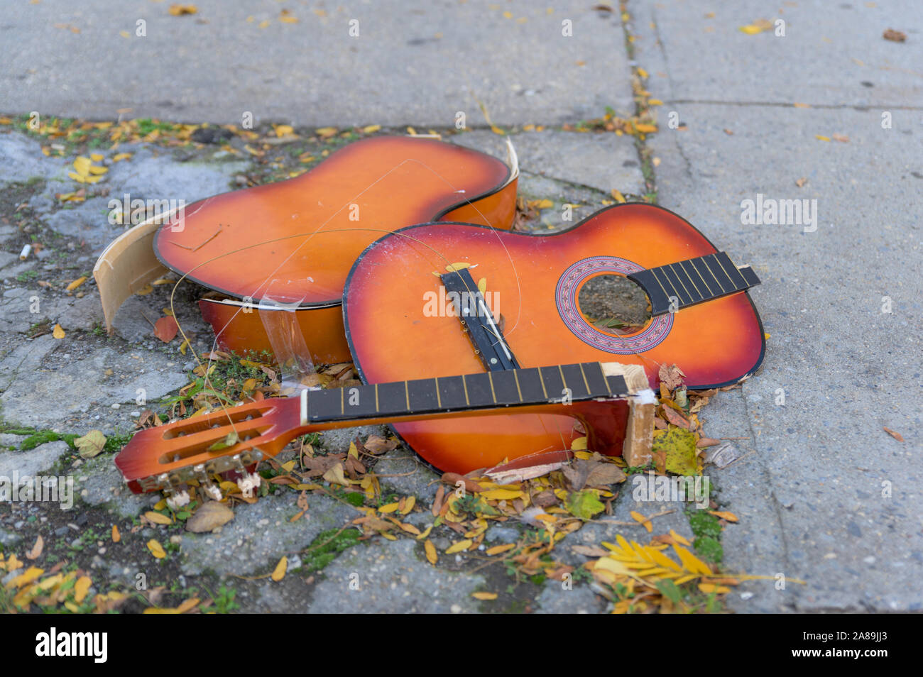 La rottura di una vecchia chitarra giacente sul calcestruzzo gettato in una New York City street Foto Stock