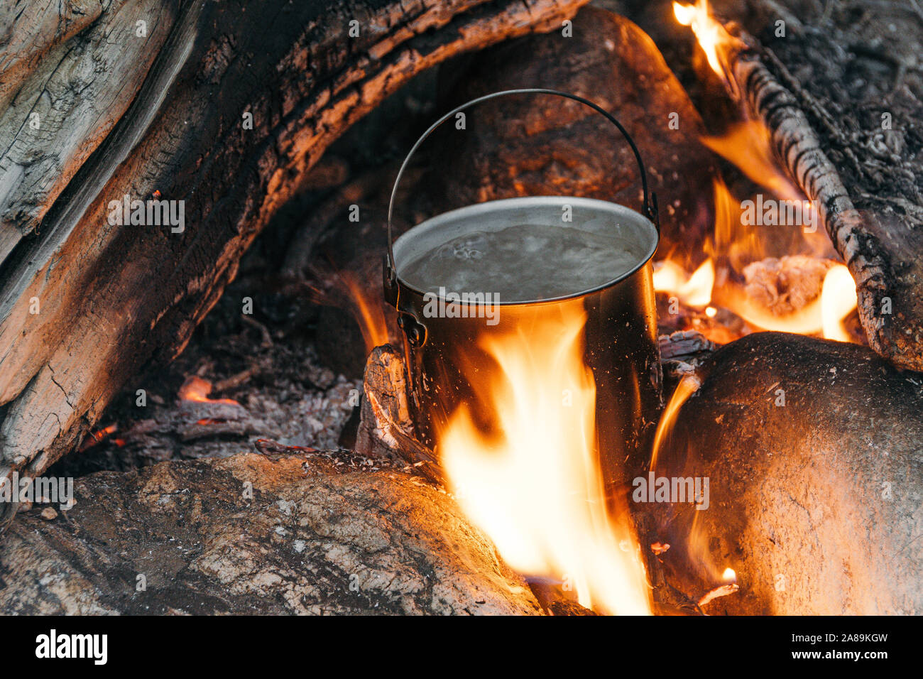 Tourist pentola sopra il fuoco. La cottura in pentole in alluminio. La sopravvivenza nel selvaggio. Foto Stock