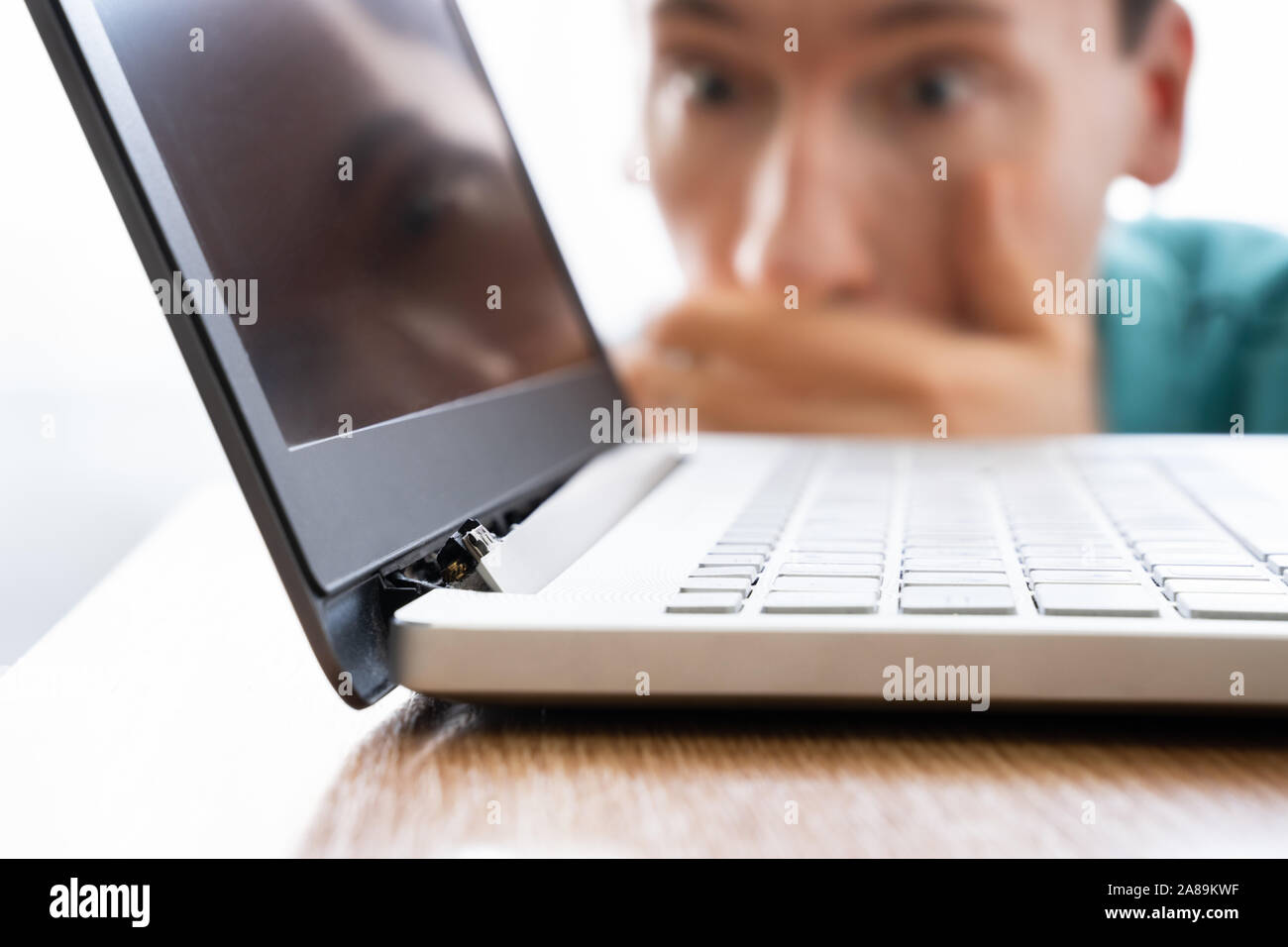 Uomo che guarda danneggiato Computer laptop con schermo rotto allegato Foto Stock