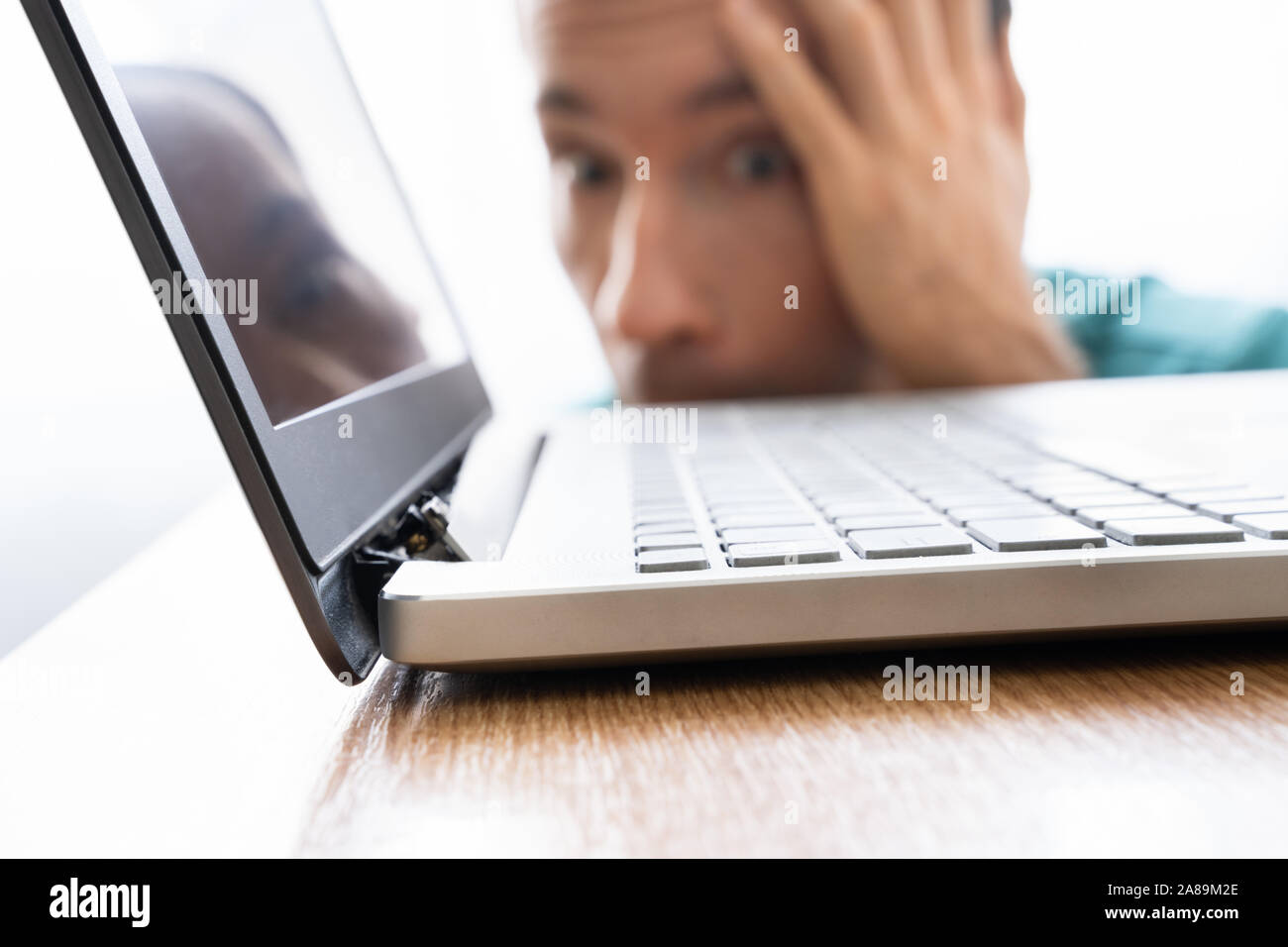 Uomo che guarda danneggiato Computer laptop con schermo rotto allegato Foto Stock