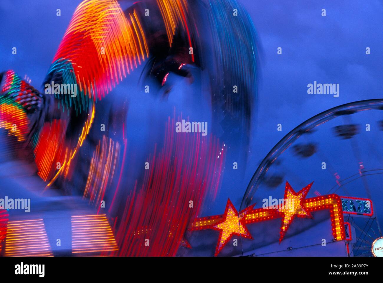 Whirling, illuminati al neon ride di carnevale al crepuscolo Foto Stock