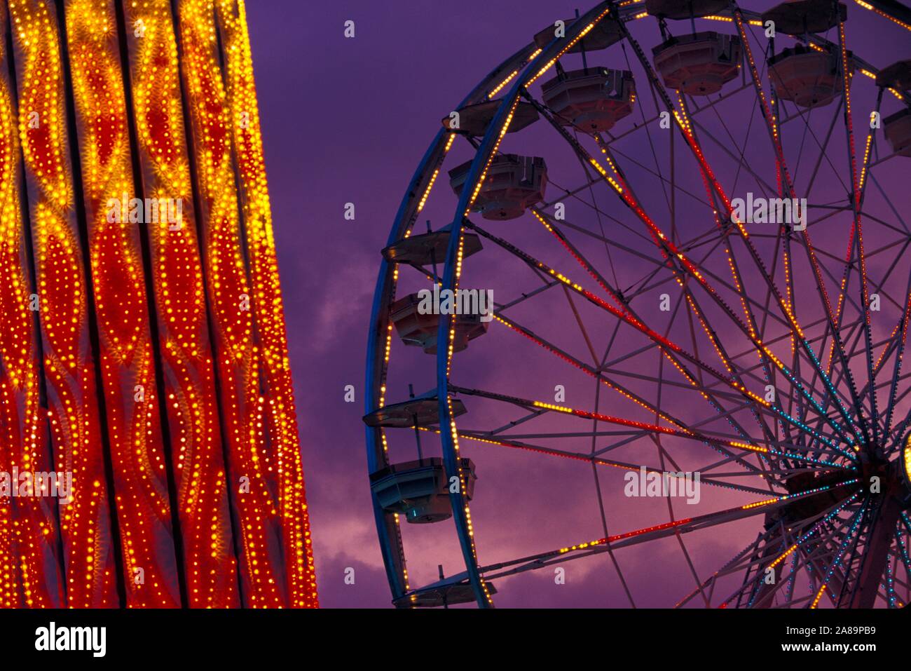 Whirling, illuminati al neon ride di carnevale al crepuscolo Foto Stock