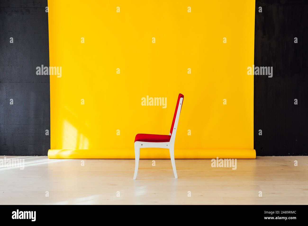 Una sedia rossa all'interno della camera con uno sfondo giallo Foto Stock