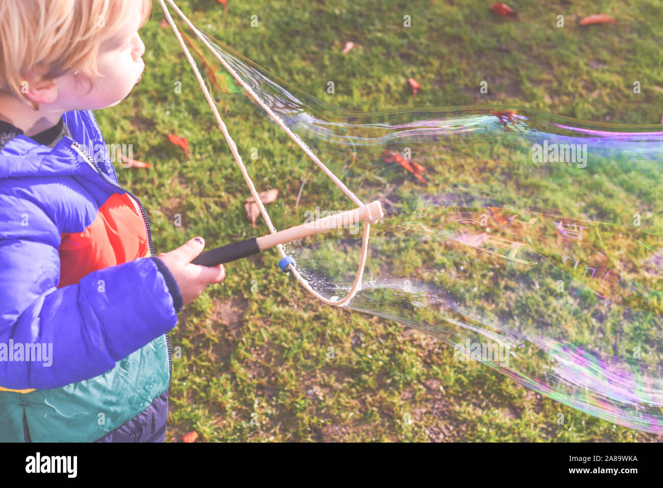 Bambini che giocano al di fuori in un giardino durante il giorno con bolle è felice e in esecuzione Foto Stock