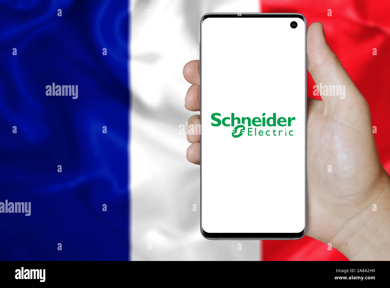 Il logo della società pubblica di Schneider Electric visualizzata su uno smartphone. Bandiera della Francia sfondo. Credito: PIXDUCE Foto Stock