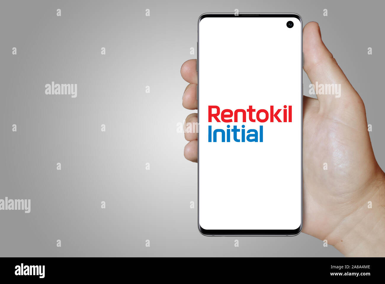 Il logo della società pubblica Rentokil Initial visualizzata su uno smartphone. Sfondo grigio. Credito: PIXDUCE Foto Stock