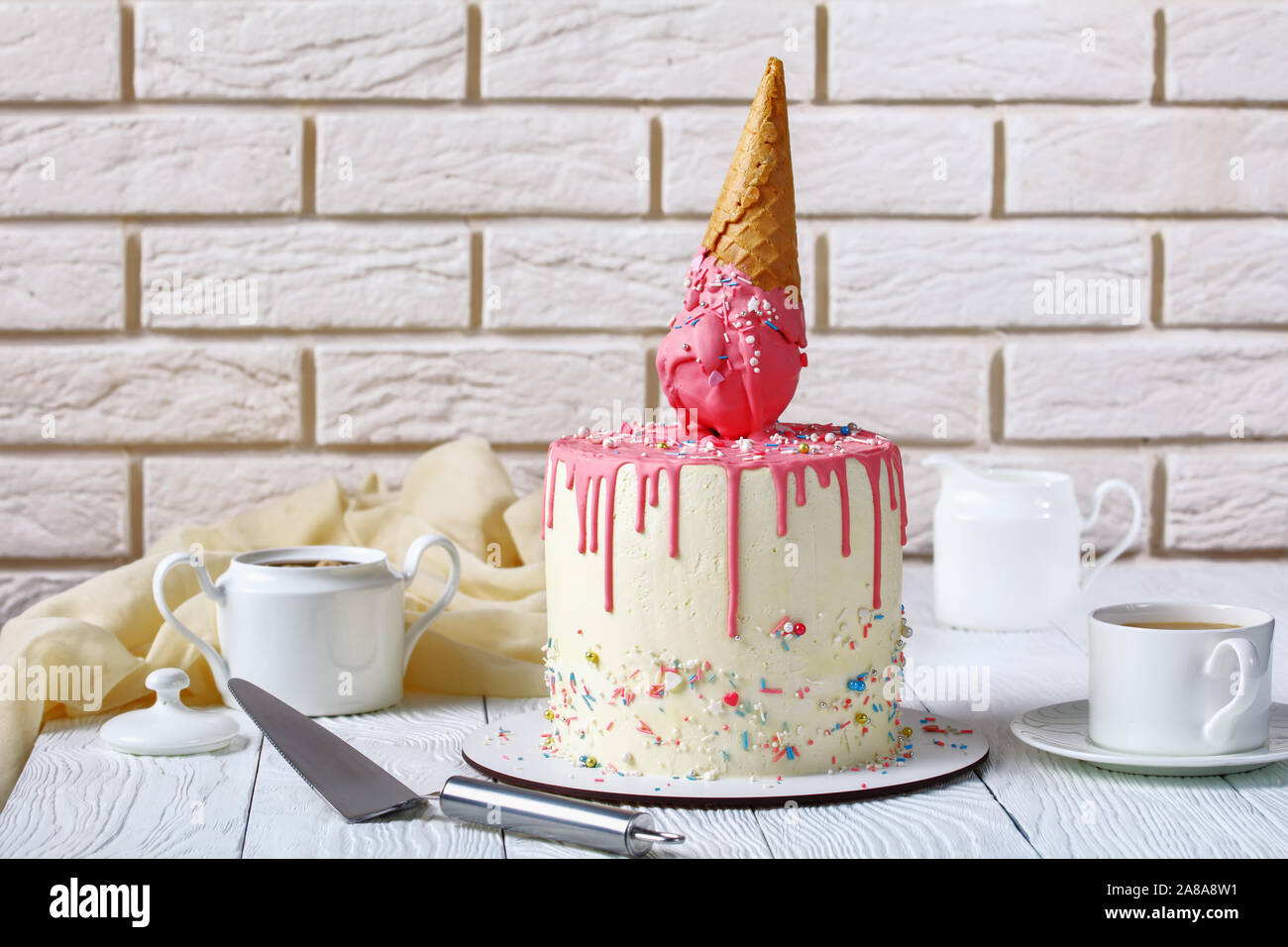 Divertente torta di compleanno con fuso il gelato in cono di cialda e glassa di gocciolamento con un muro di mattoni in background Foto Stock