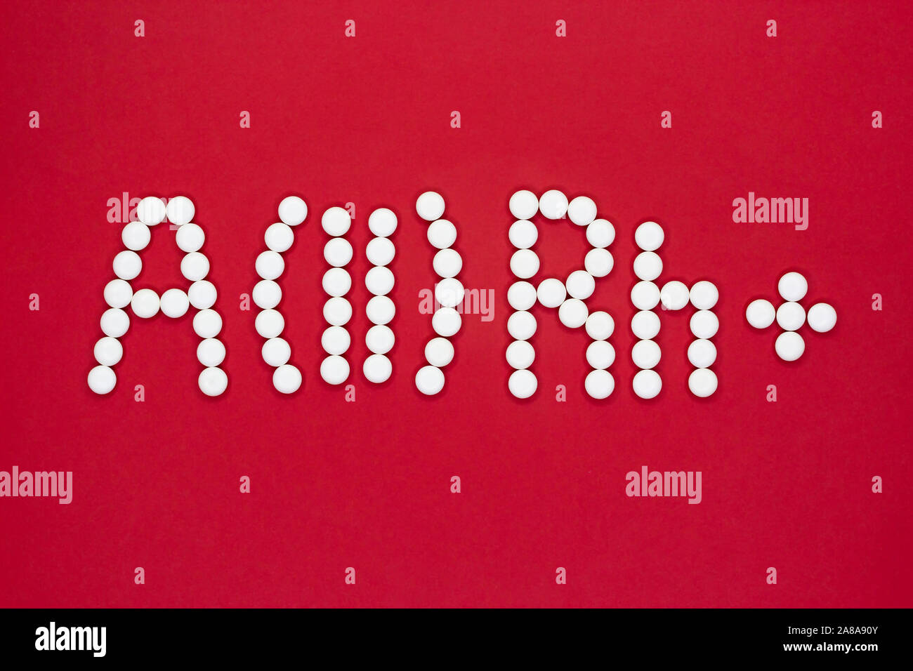 Secondo tipo di sangue. Simbolo del tipo di sangue da pillole bianche su sfondo rosso. Trattamento del tipo di sangue. Foto Stock