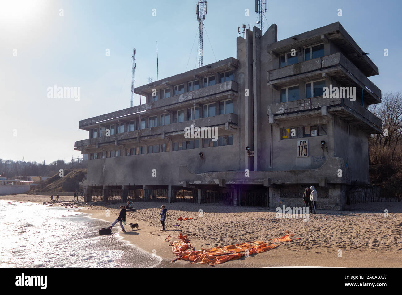 Porta abbandonato edificio con torri mobili in riva al mare. Le figure di turisti non sono identificati Foto Stock