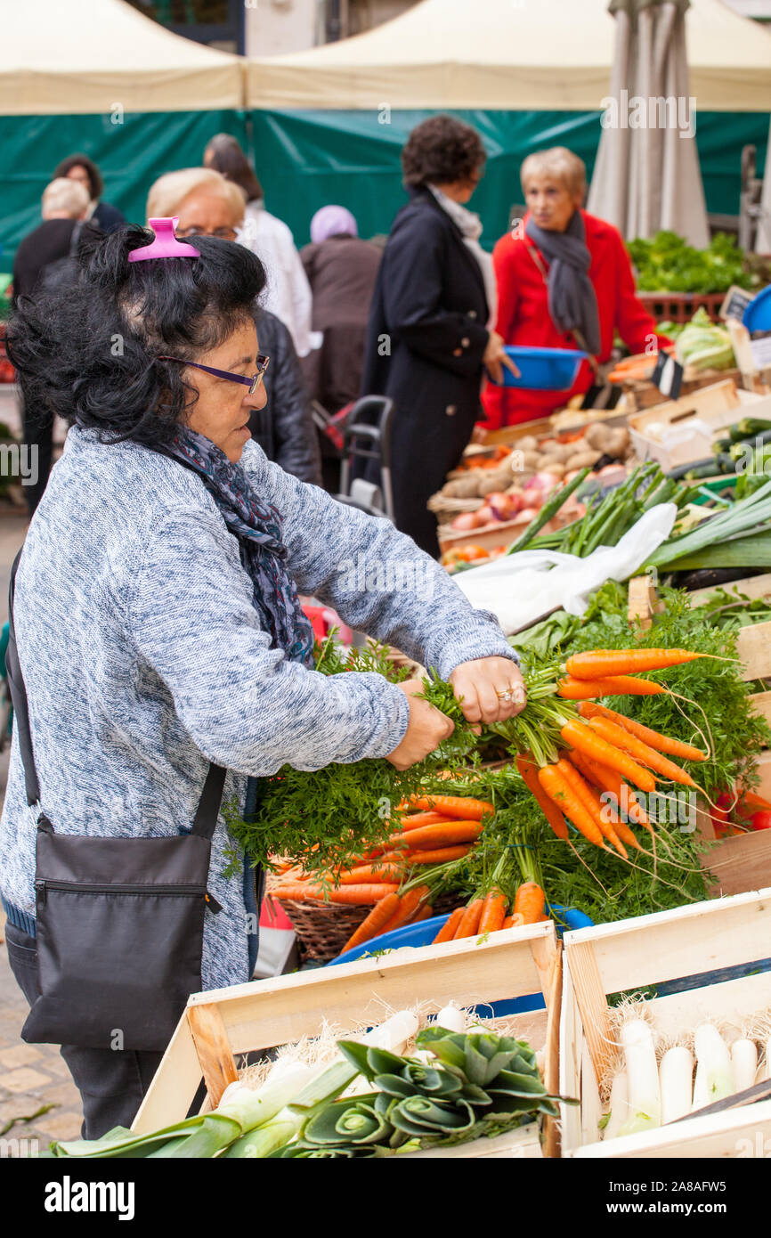 Mercato proprietario di stallo la torsione delle cime di freschi Carote su un mercato in stallo nella cittadina francese di Carcassonne FRANCIA Foto Stock