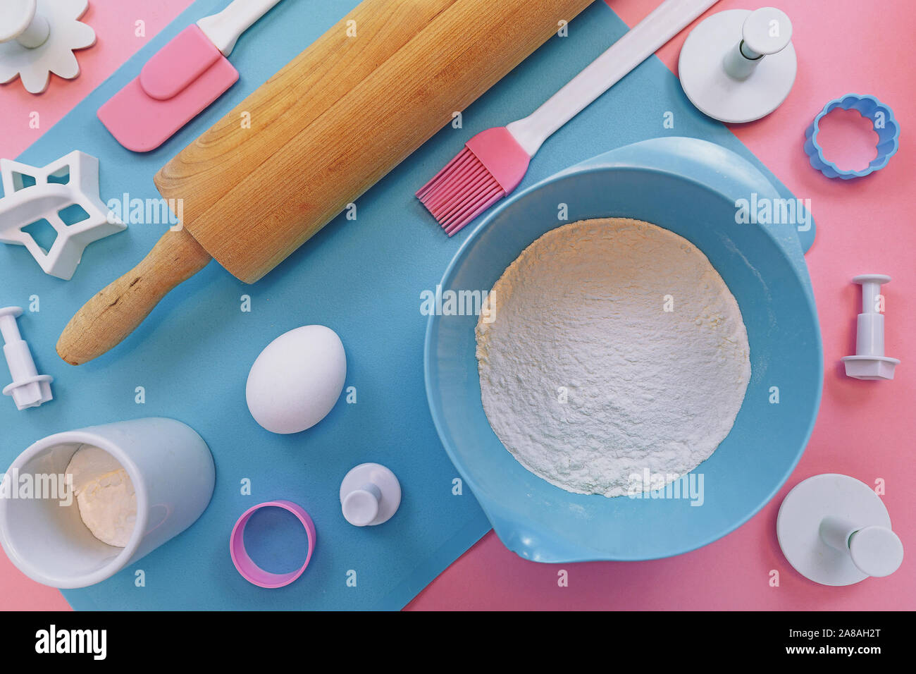 Vista superiore piatta con laici carino rosa e blu di utensili di cottura come la laminazione di legno pin, cookie cutter o ingredienti come la farina in un recipiente e uovo Foto Stock