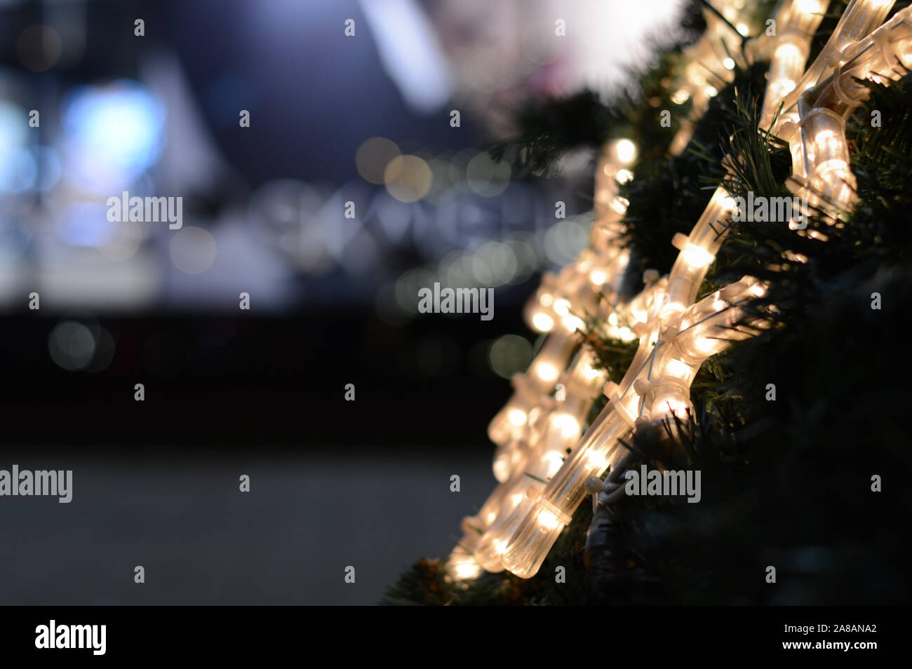Sfocate e non focalizzata, astratta di festa con sfondo bianco led al neon  con il simbolo del fiocco di neve su di un albero di Natale, di notte le  luci della città