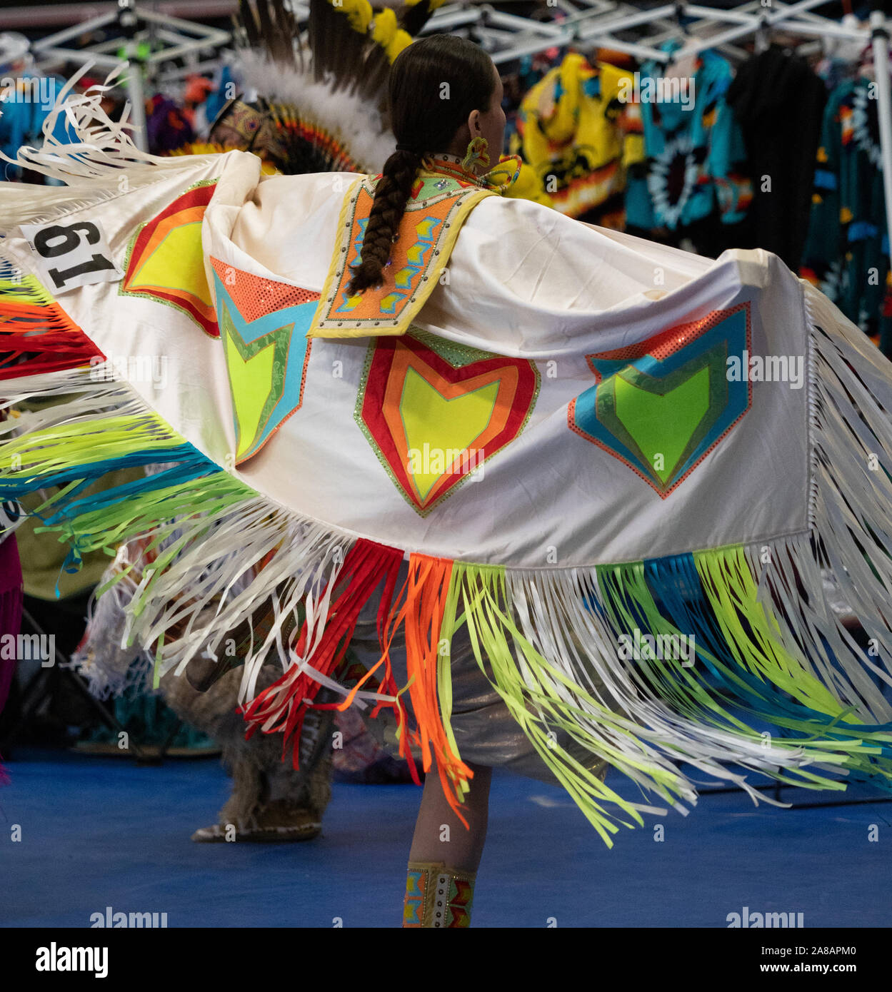 Native American donna con capelli intrecciati dancing a Pow Wow con bianco,  neon di arancione e giallo, rosso e blu ribbon scialle. Fotografato da  dietro Foto stock - Alamy