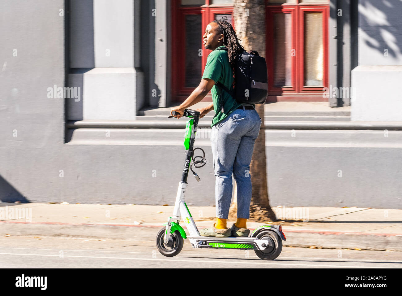 Novembre 2, 2019 San Francisco / CA / STATI UNITI D'AMERICA - il giovane uomo a cavallo di un lime scooter nel centro cittadino di San Francisco; calce è il marchio con il quale le aziende di neutroni, Foto Stock