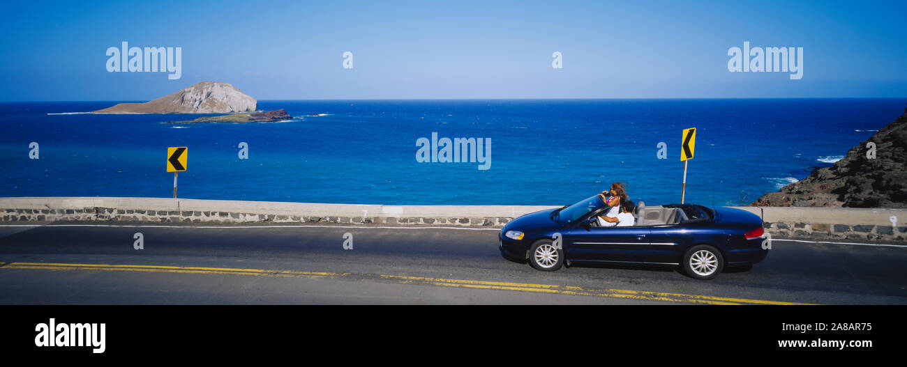 Profilo laterale di una giovane in Viaggio in autovettura convertibile, Isola dei Conigli, Makapuu, Hawaii, STATI UNITI D'AMERICA Foto Stock