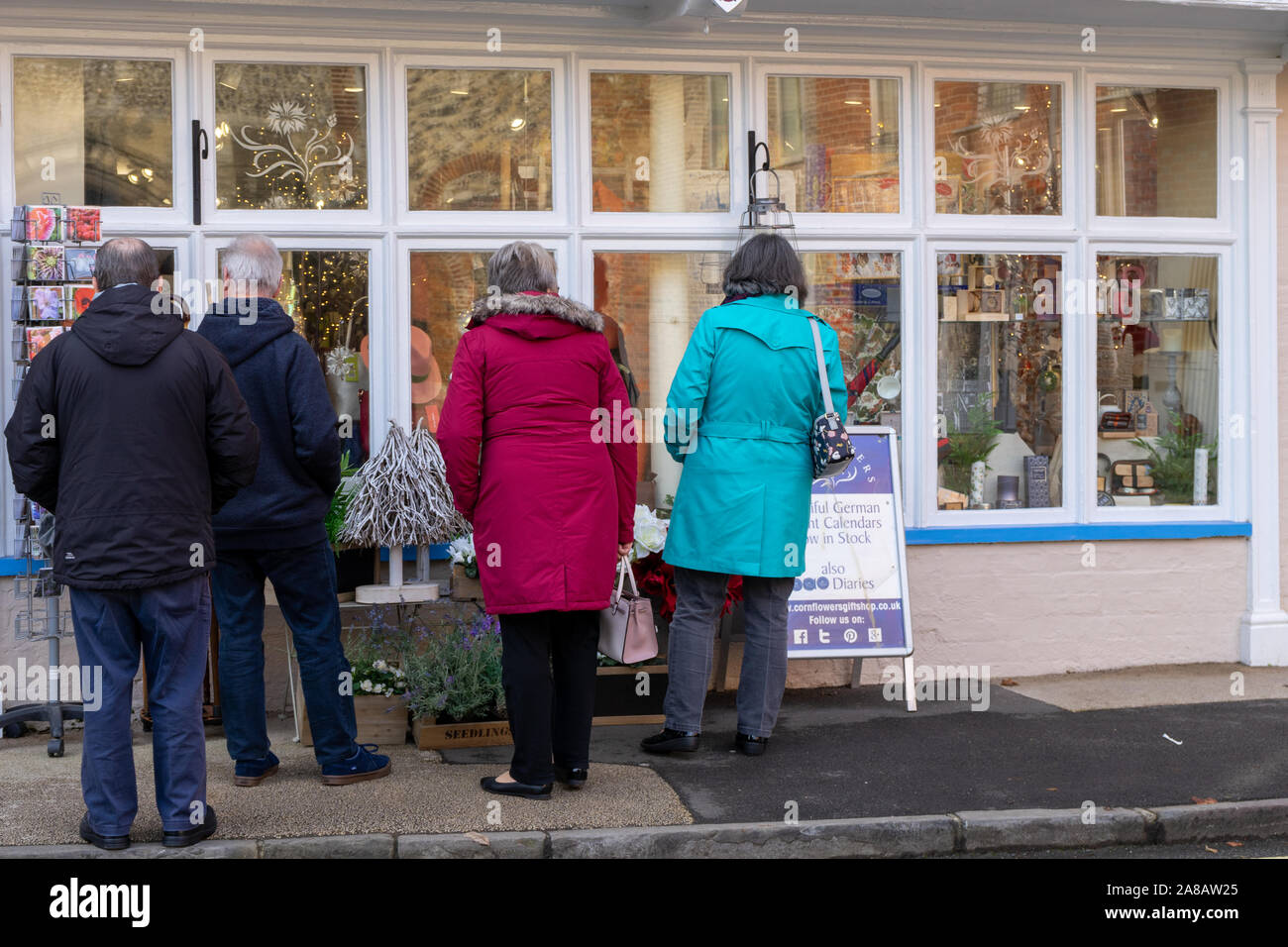 due coppie di mezza età che guardano nella finestra di a. Pittoresco negozio inglese Foto Stock