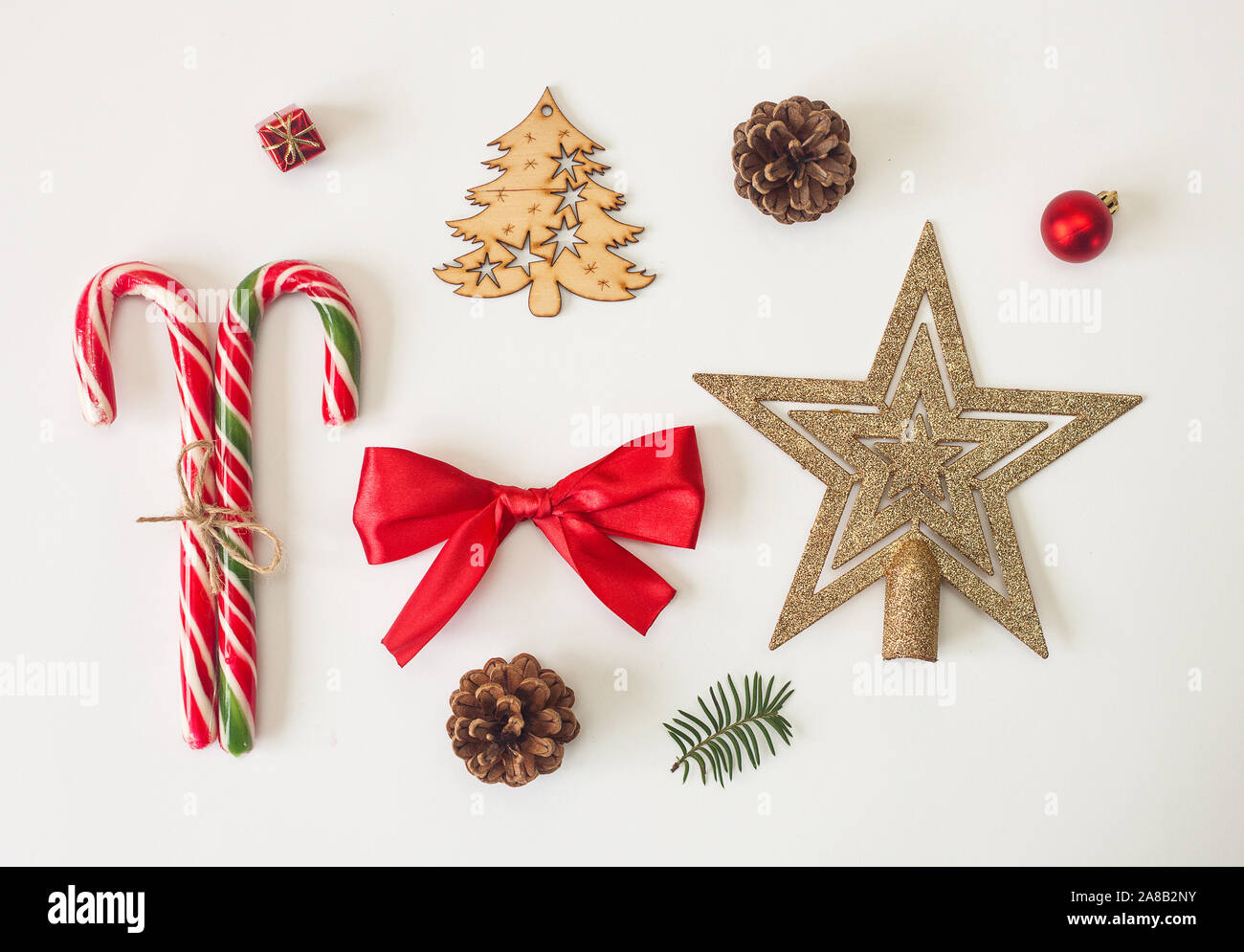Holiday stuff, caramelle, nastri, arco rosso, decorazioni natalizie e cono di pino su sfondo bianco. Set di oggetti di design della scheda. Foto Stock