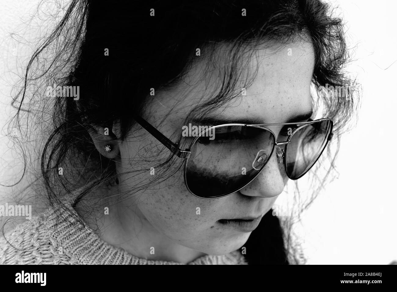Giovane ragazza guarda pensieroso indossando occhiali da sole in bianco e nero Foto Stock