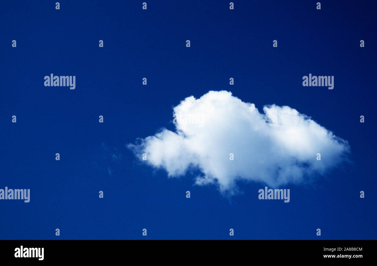Singola nuvola bianca contro il cielo blu Foto Stock