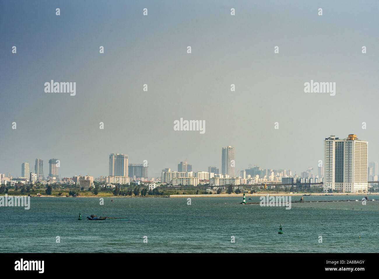 Da Nang, Vietnam - Marzo 10, 2019: Tien Sa Porto di Da Nang Bay. Skyline della città come urban banda di pietra che separa un mare azzurro dalla luce blu del cielo. Alcuni verde Foto Stock