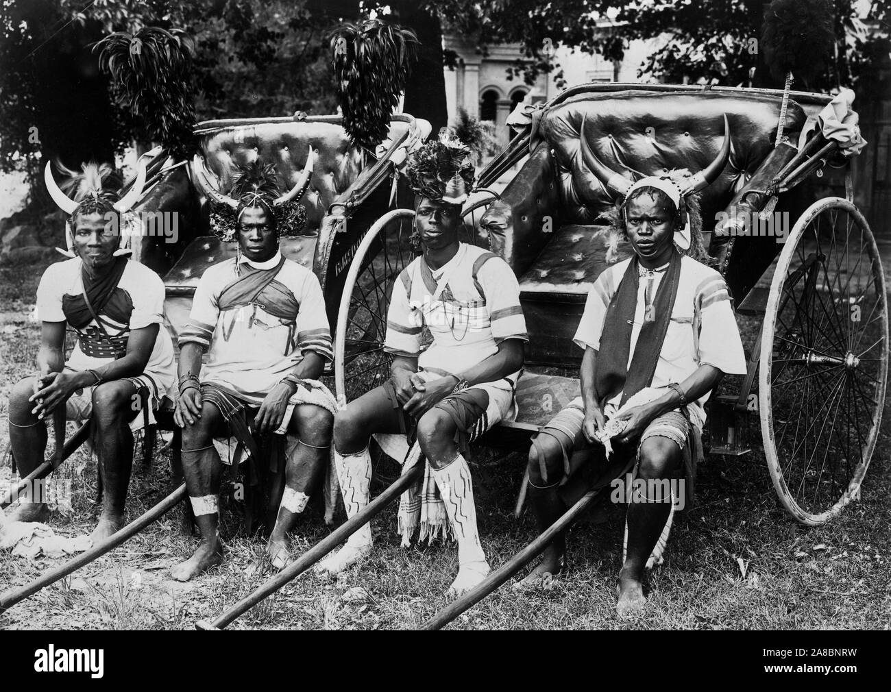 Ragazzi Ricksha Durban, Sout Africa 1890-1923 Foto mostra quattro giovani uomini seduti nella parte anteriore del riscio, rivolto verso la parte anteriore, tre sono cornuto da indossare copricapo e il quarto è che indossa un copricapo floreale. Foto Stock