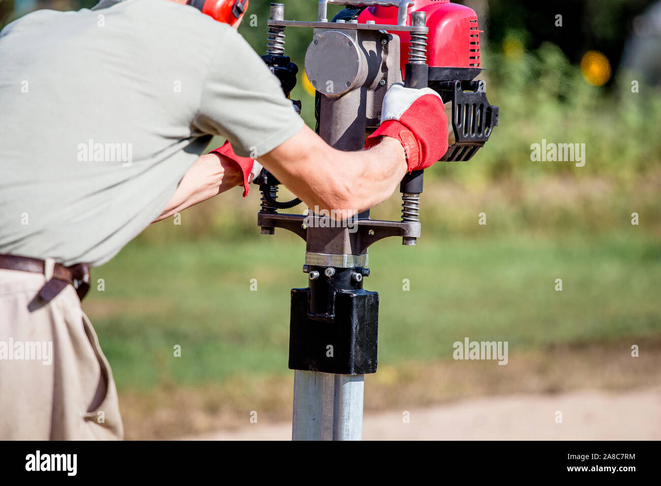 Uomo che utilizza un utensile manuale per l'espansione di pali a benzina all'aperto sul cantiere. Foto Stock