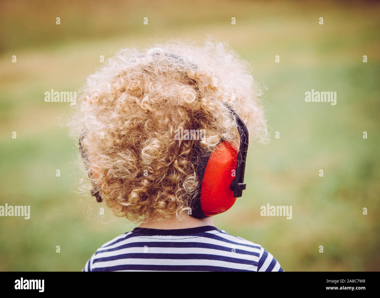 I bambini più piccoli indossano cuffie antirumore al concerto all'aperto, evitando la perdita dell'udito in età giovanile. Foto Stock